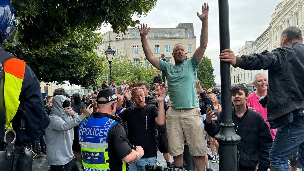 A man raises his arms during a protest in the UK