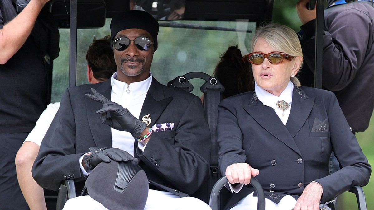 Snoop Dogg and Martha Stewart in matching horseback riding outfits riding a golf cart together