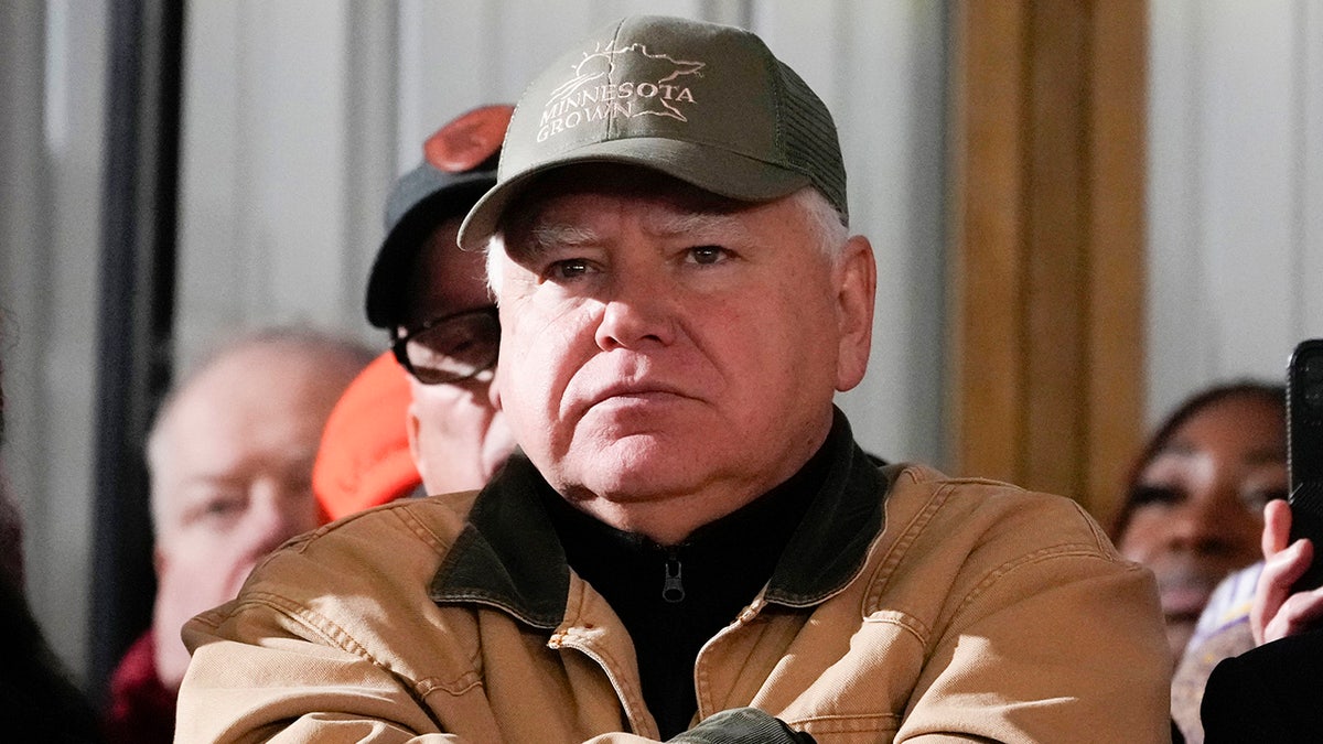 Tim Walz con abrigo y gorra de granjero en primer plano