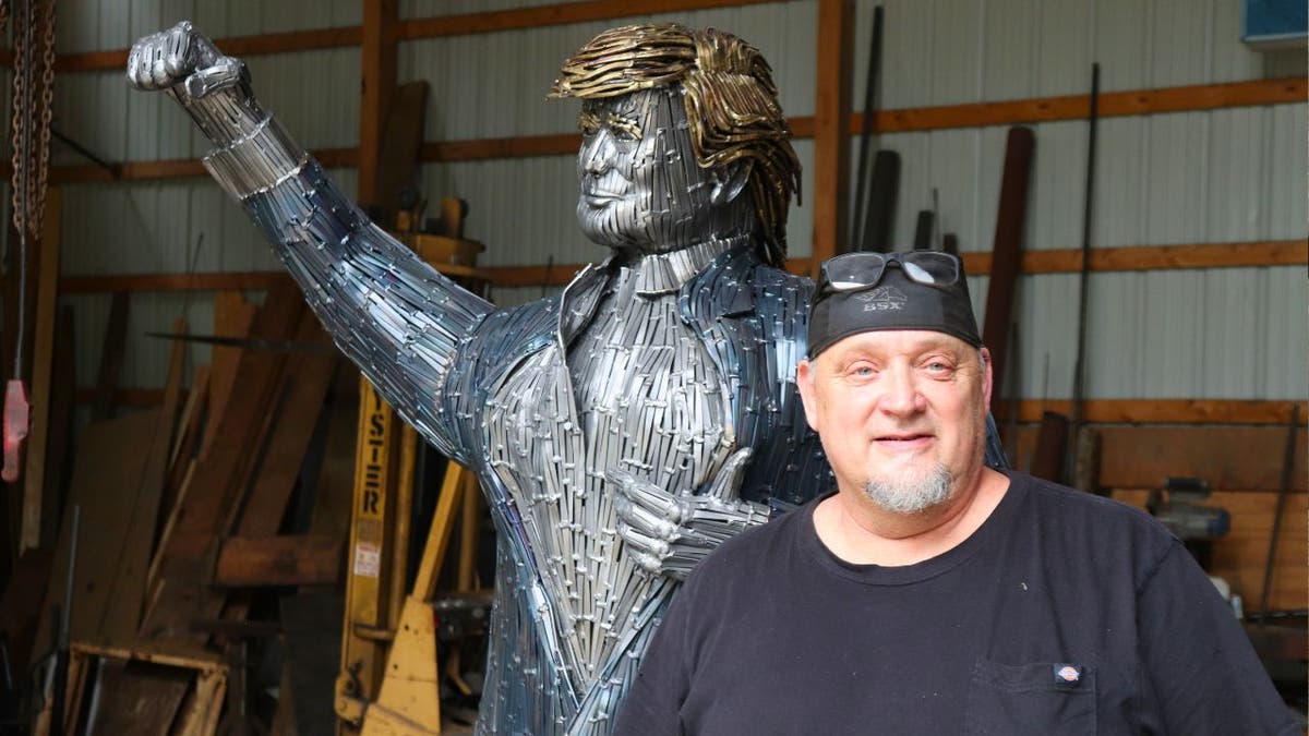 Butler artist Bill Secunda stands in front of a nail structure of former President Trump.