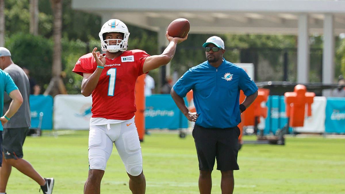 Tua Tagovailoa throws the ball as Brian Flores watches