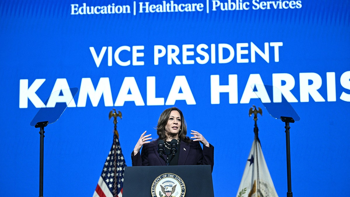 Kamala Harris hablando bajo un gran cartel azul