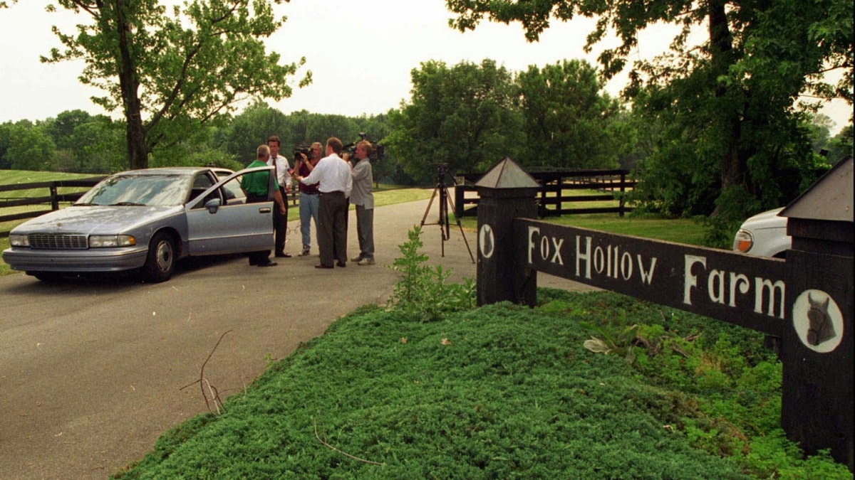 2 de julio de 1996; Westfield, IN; Los medios de comunicación televisivos entrevistan a un agente de policía frente a la entrada de la granja Fox Hollow de Westfield, donde la semana pasada se descubrieron huesos humanos. Las autoridades siguen investigando la escena.