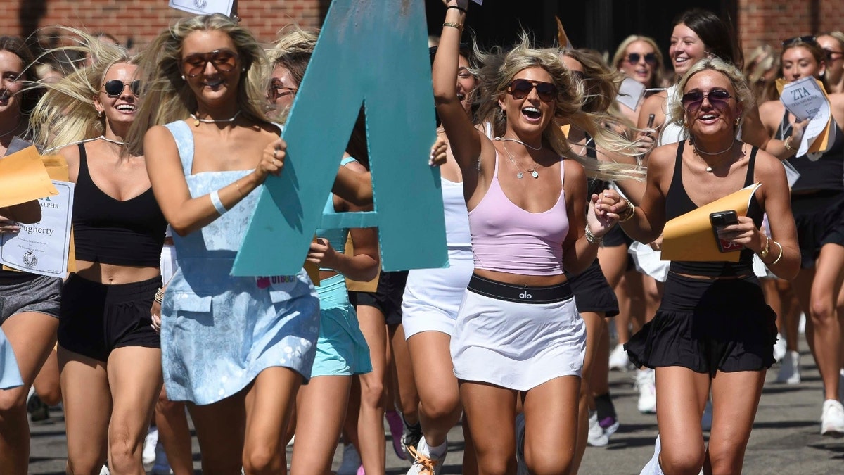 New members of Zeta Tau Alpha run to their house after opening their bids in Bryant-Denny Stadium.