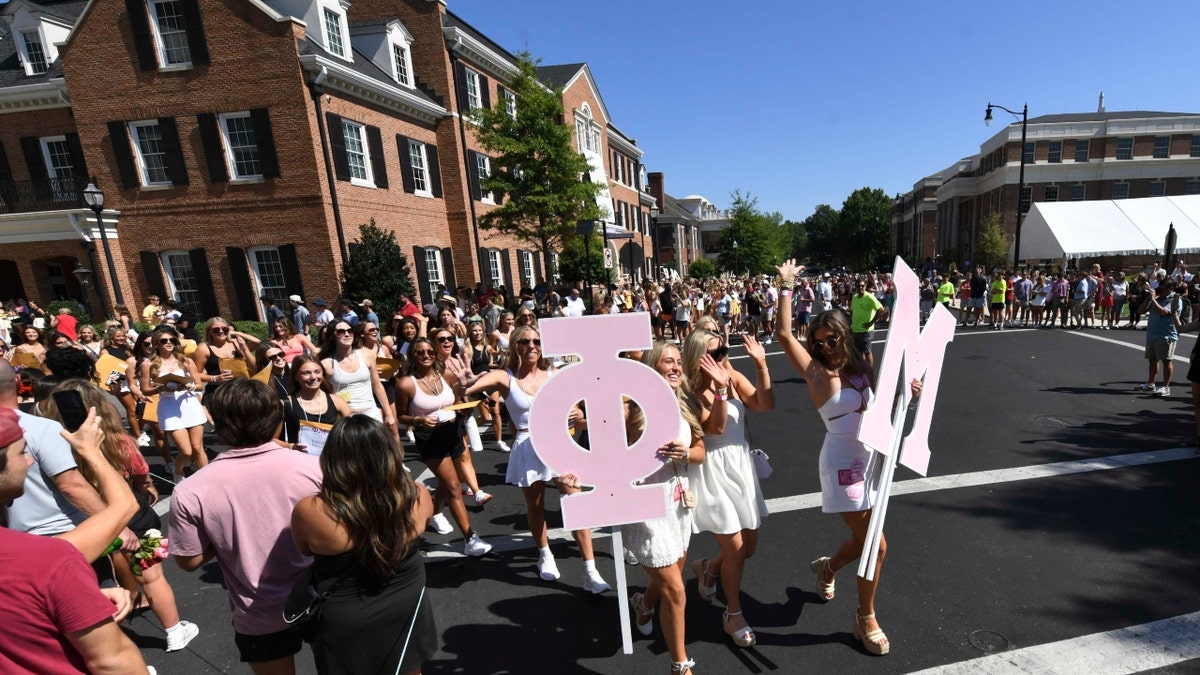 Los nuevos miembros de Phi Mu caminan hacia su casa tras recibir sus ofertas en el estadio Bryant-Denny.