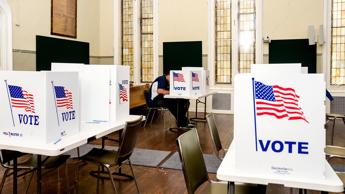 sala llena de cabinas de votación sobre mesas