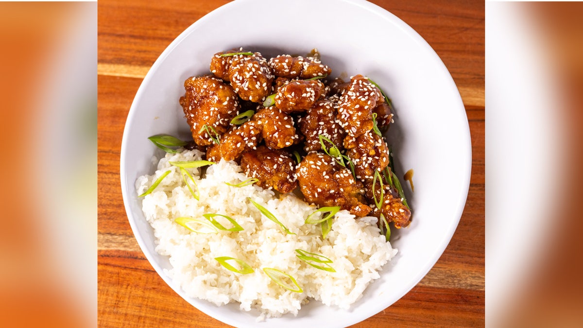 Un plato de pollo chino con sésamo servido con arroz blanco.