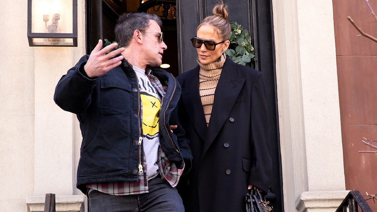 Ben Affleck with his hands up looks back and speaks to wife Jennifer Lopez in a black peacoat in New York