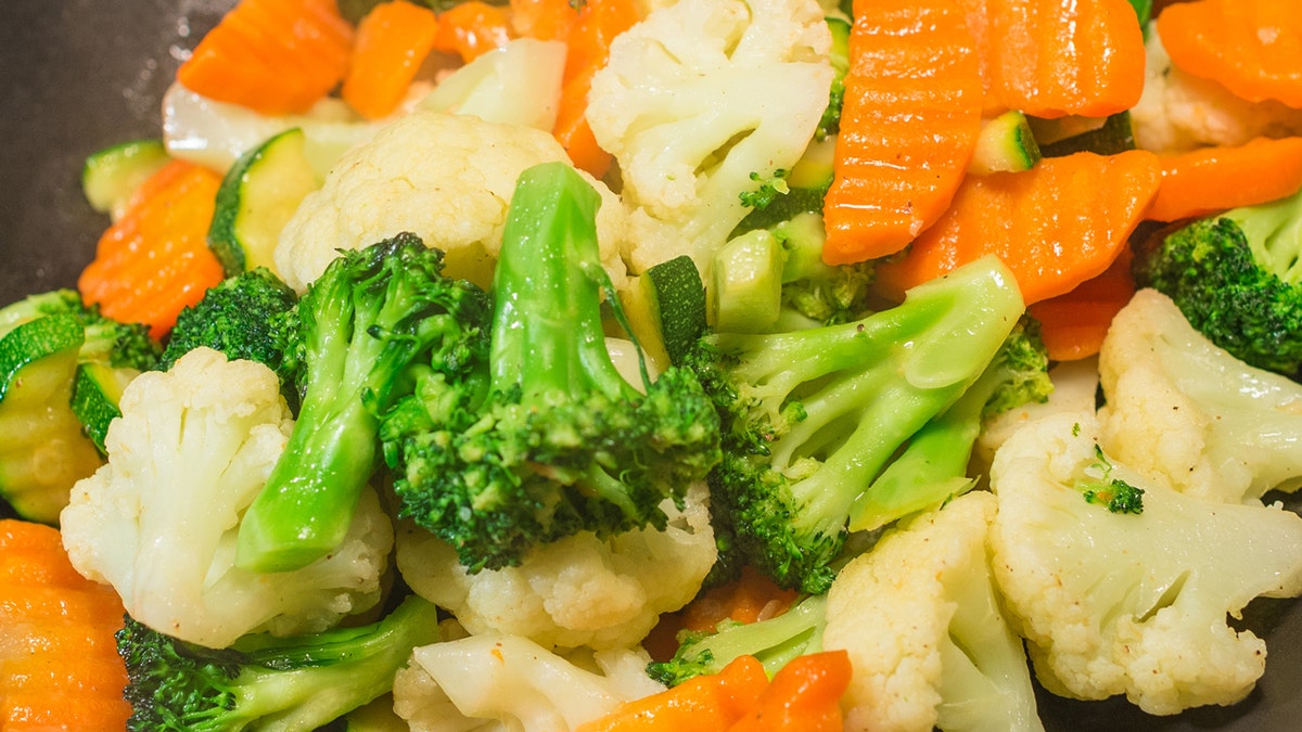 Este es un primer plano del brócoli, la coliflor y las zanahorias en un salteado de verduras arco iris.