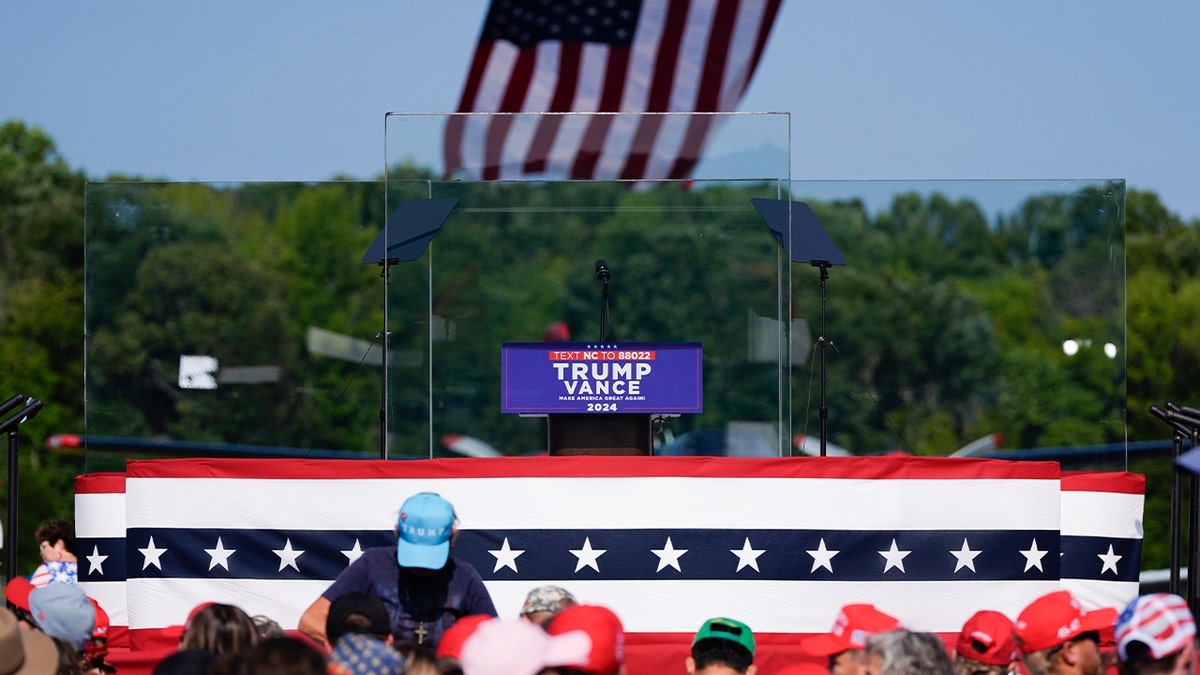 Um palco ao ar livre é montado envolto em vidro à prova de balas enquanto os apoiadores chegam para ouvir o candidato presidencial republicano, ex-presidente Donald Trump, falar em um comício, quarta-feira, 21 de agosto de 2024, em Asheboro, Carolina do Norte. Trump está realizando seu primeiro comício ao ar livre desde que sobreviveu por pouco a uma tentativa de assassinato quando um atirador abriu fogo na Pensilvânia no mês passado.