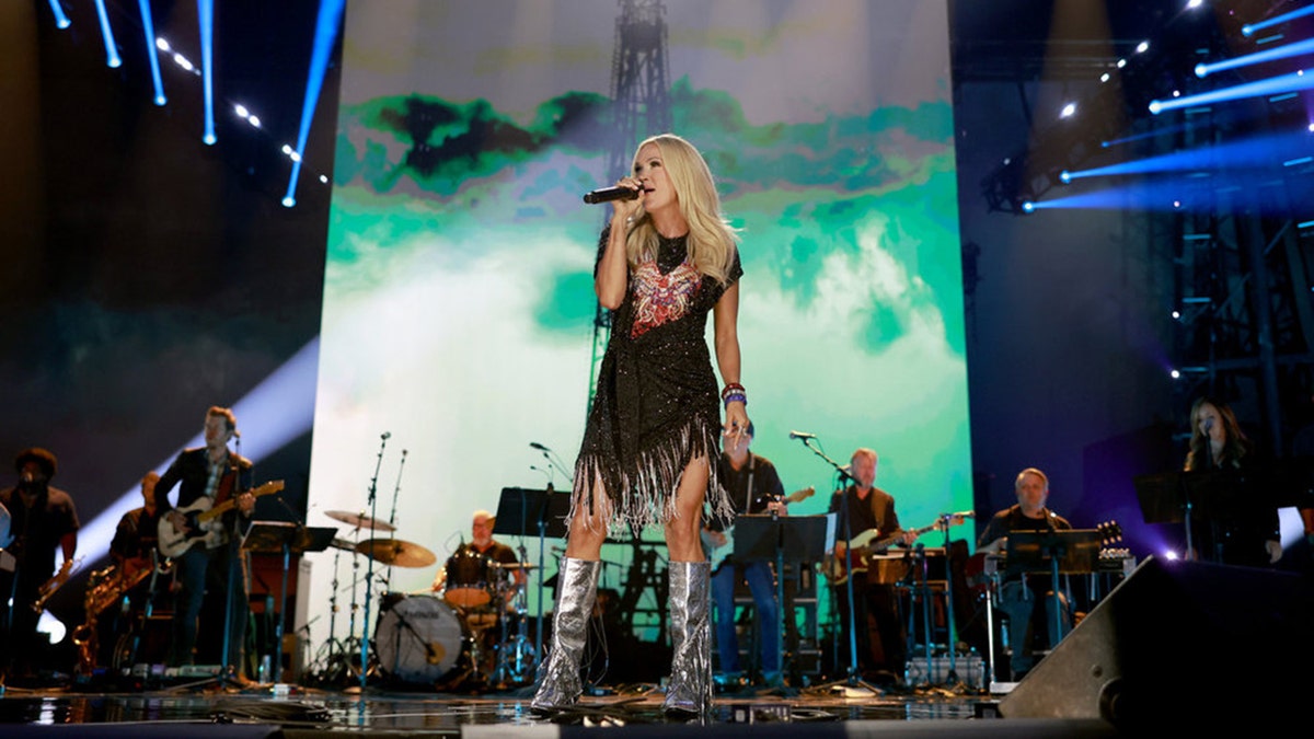 American Idol judge Carrie Underwood wears silver boots and a black dress during the Toby Keith tribute.