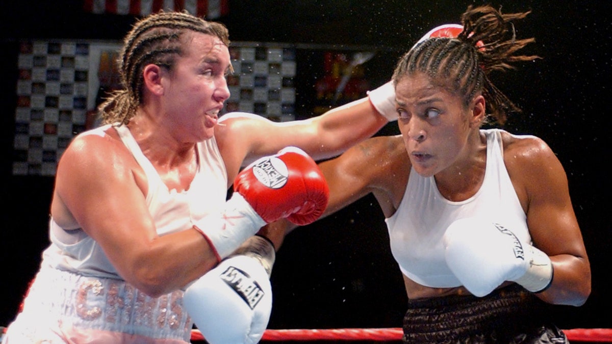 Christy Martin con trenzas en el pelo pelea con Laila Ali, ambas vestidas de blanco