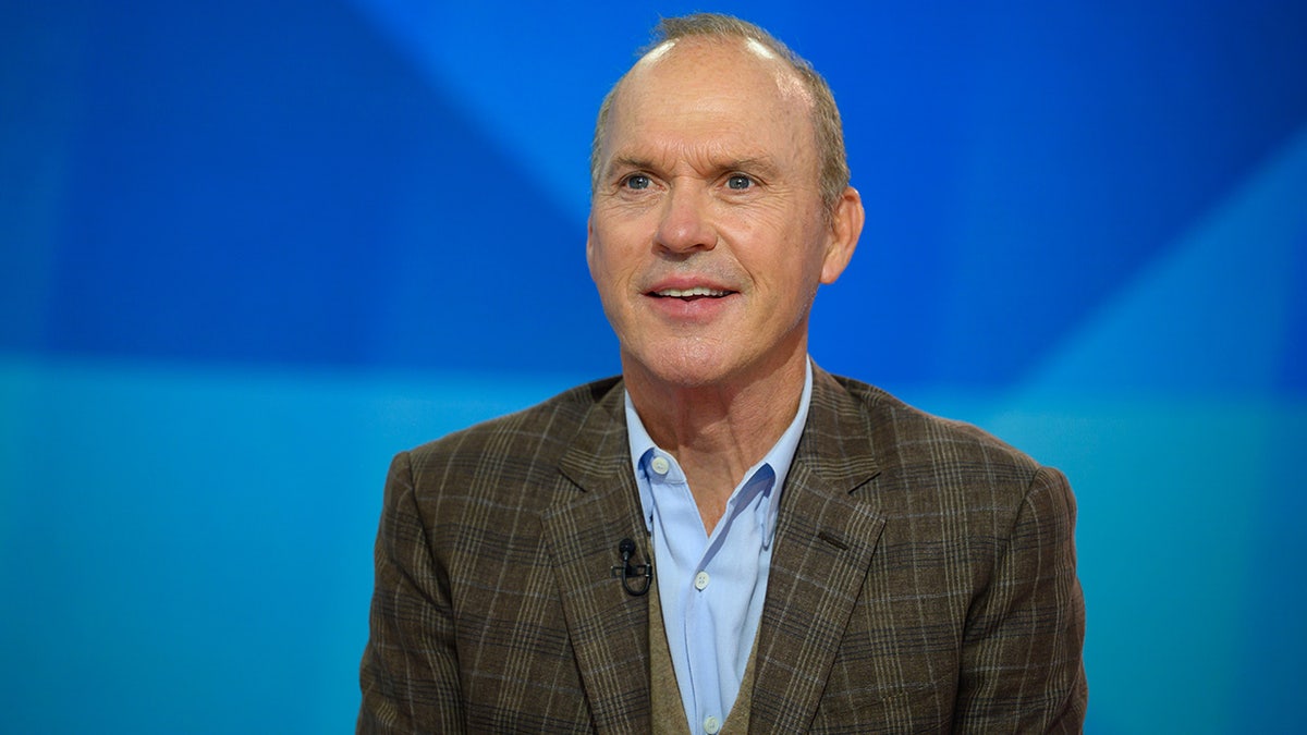 Michael Keaton in a patterned green jacket and blue shirt looks up while on the TODAY show