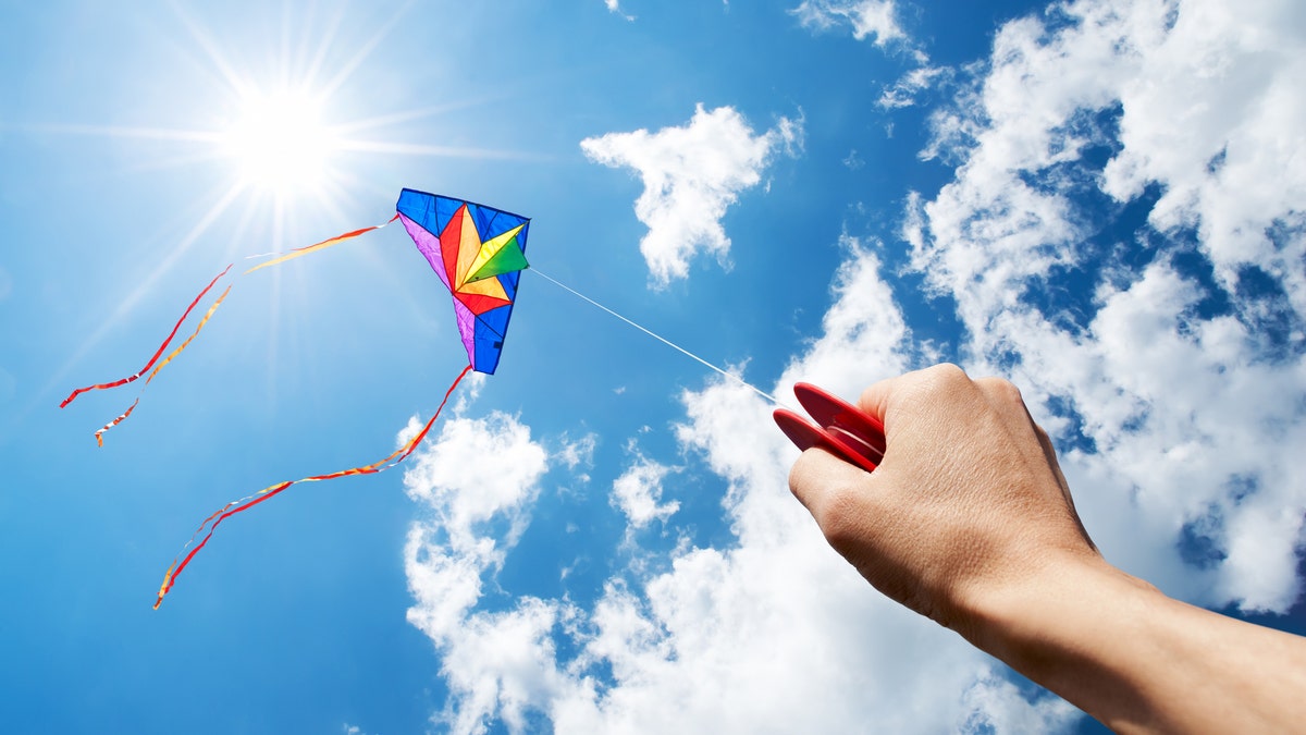 Kites fly in the sky, the sun shines in the background