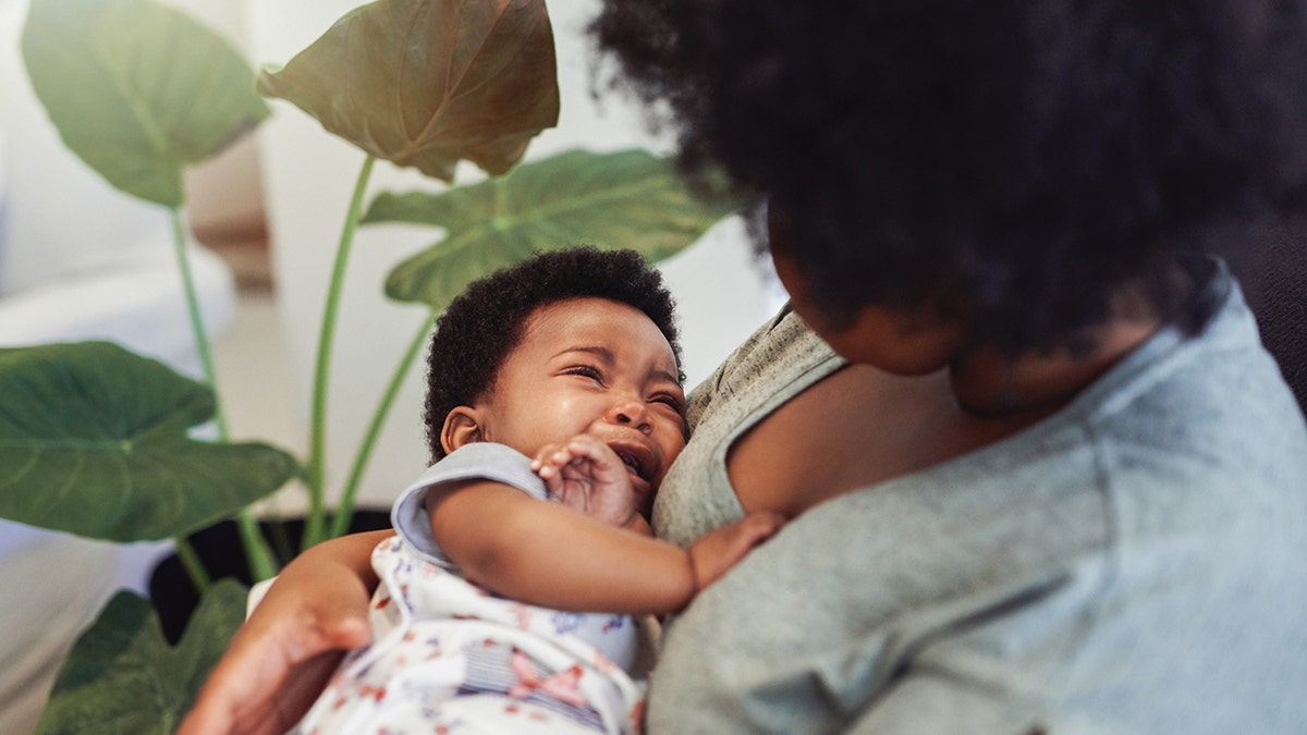 baby cries in mother's arms