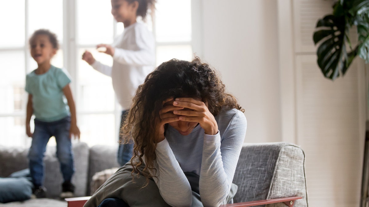 Mom stressed by kids jumping on the couch