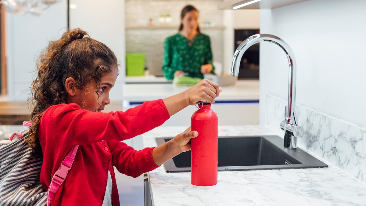 Child fills up her water bottle from the sink.