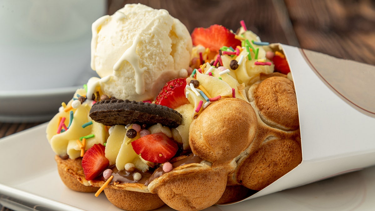 Hong kong o gofre de burbujas con helado, frutas, salsa de chocolate y caramelos de colores.