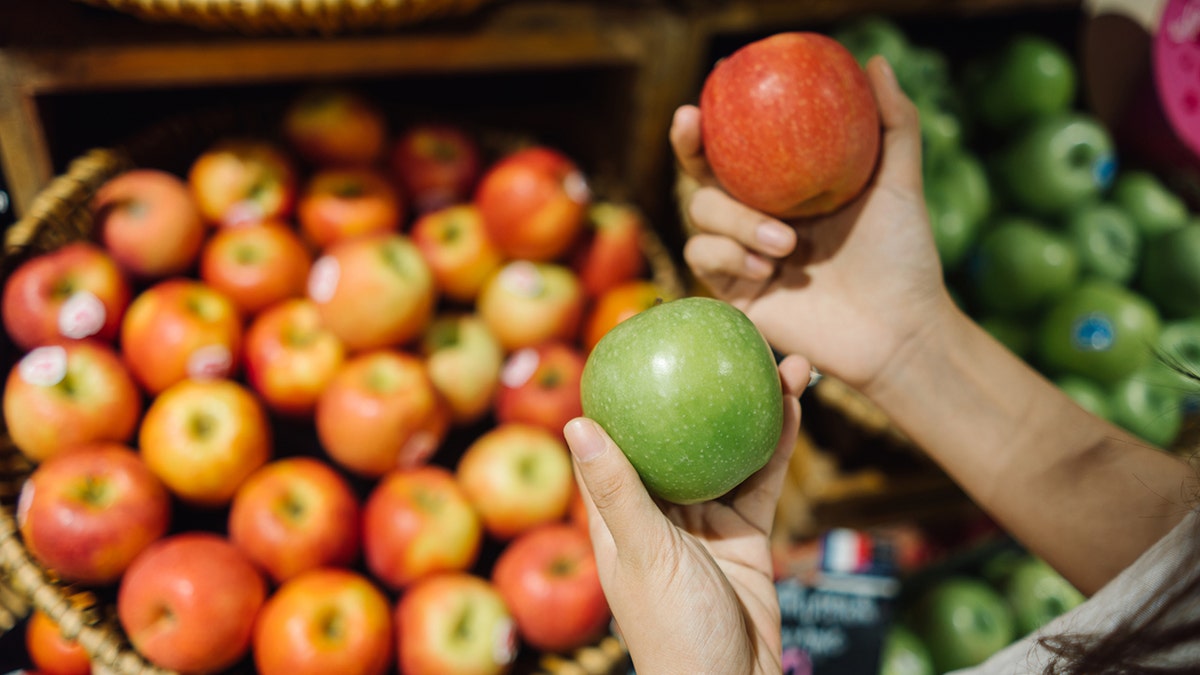 Two hands holding red and green apples.