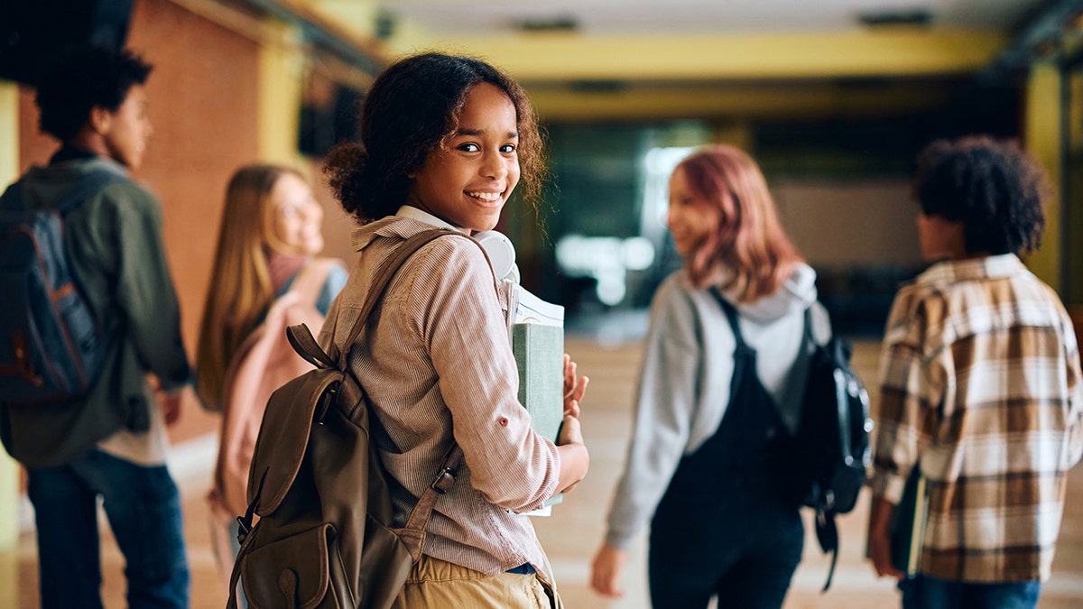 Estudiante de secundaria feliz caminando por el pasillo con sus amigas