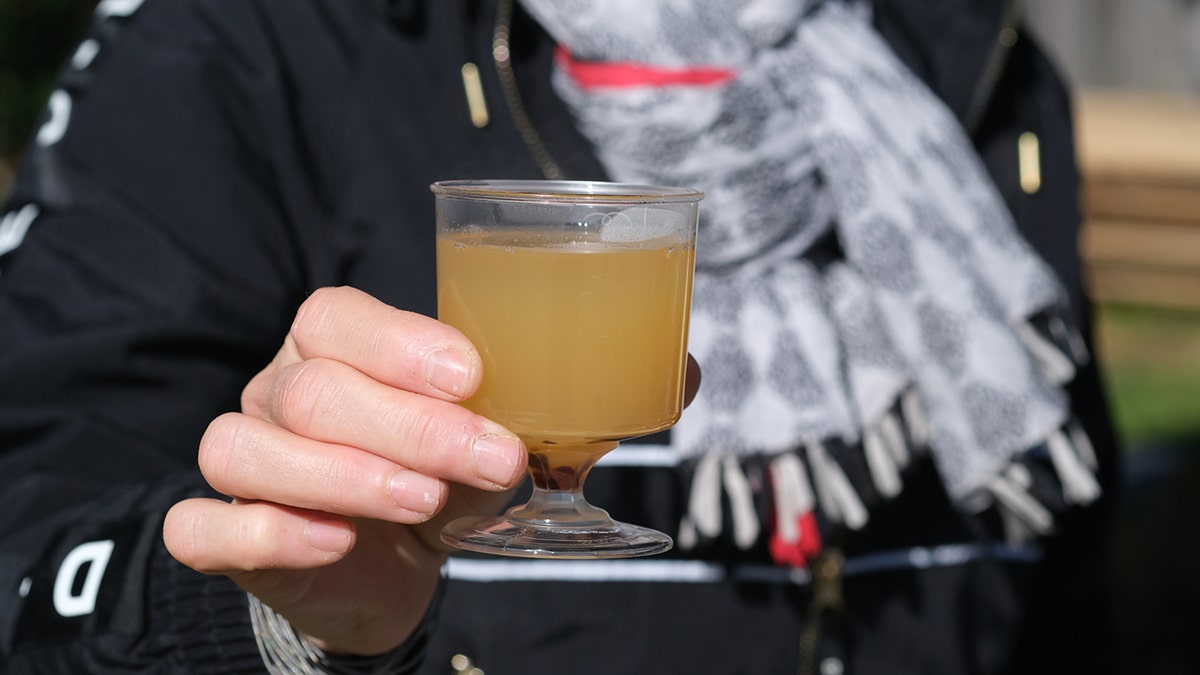 Person holding glass of mead.
