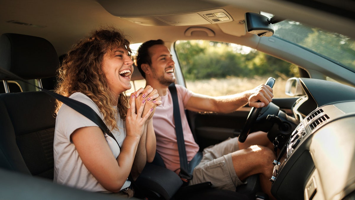 Pareja joven riendo durante su aventurero viaje en coche.