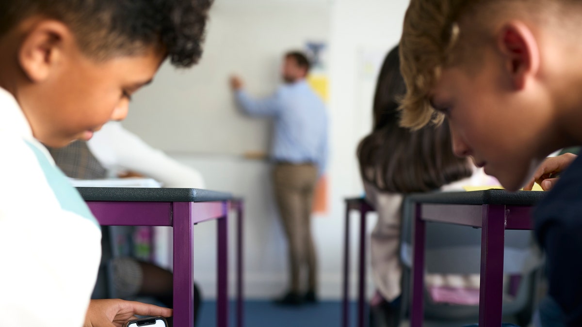 niños en clase distraídos por teléfonos