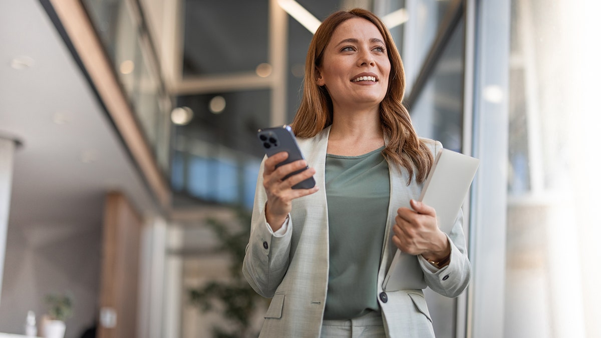 wanita bisnis dengan telepon dan portofolio di kantor