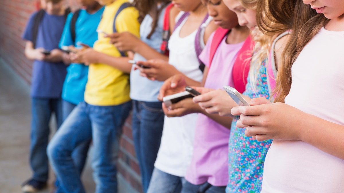 niños pequeños con teléfonos fuera de la escuela