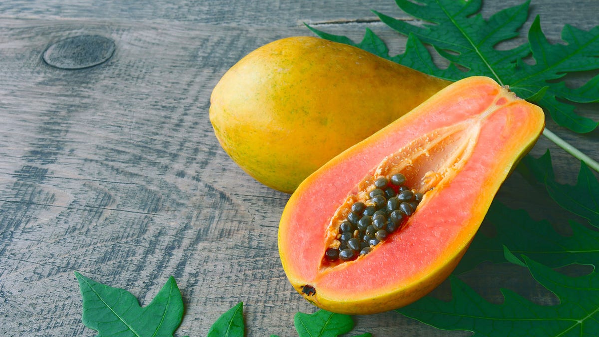 A picture of a papaya cut in two on a table.