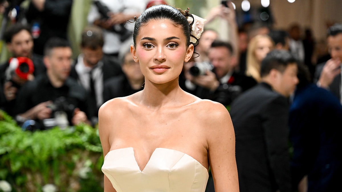 Kylie Jenner in a cream strapless dress looks directly at the camera on the Met Gala carpet