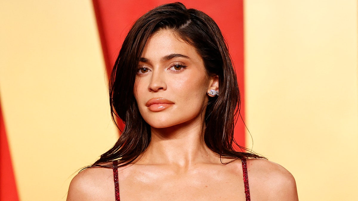 Kylie Jenner in a red strap dress at the Vanity Fair Oscar party looking directly at the camera 