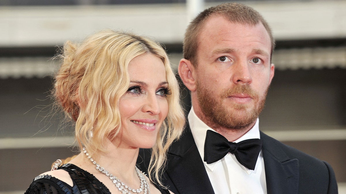 Madonna in a black dress looks away from the camera next to her husband Guy Ritchie in a classic tuxedo in Cannes