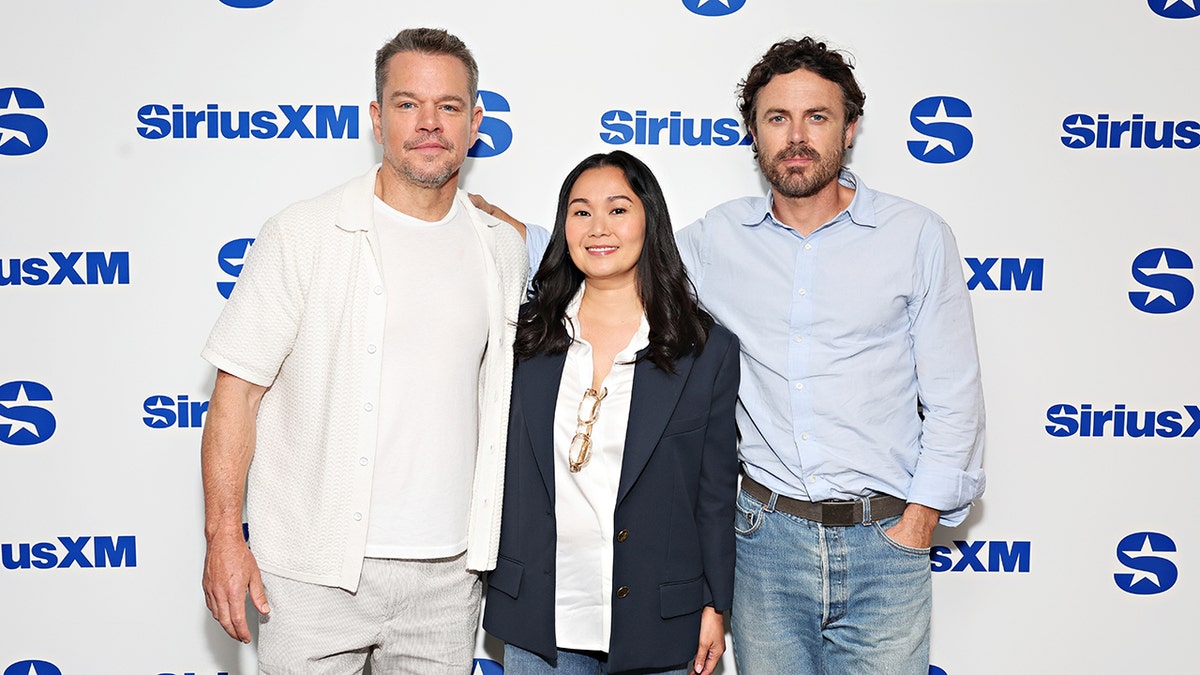 Matt Damon, con camisa blanca, sonríe suavemente con sus coprotagonistas Hong Chau, con americana azul marino, y Casey Affleck, con camisa azul claro