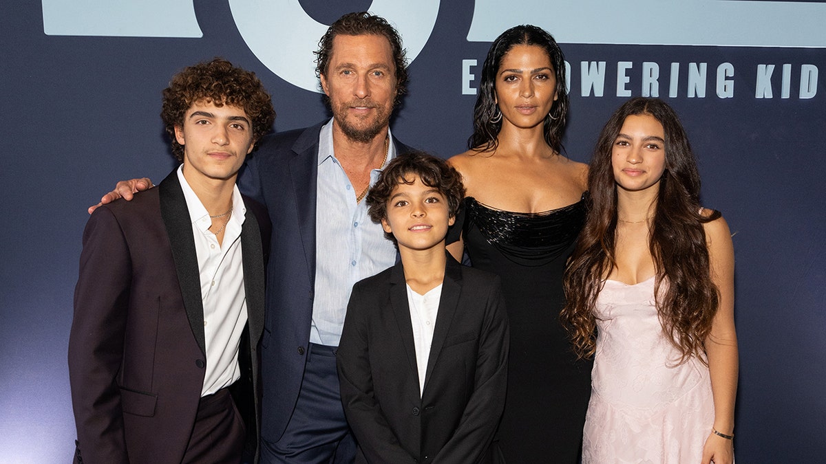 Matthew McConaughey in a blue blazer poses with his wife Camila in a black dress and their three children, Levi, Livingston, and Vida