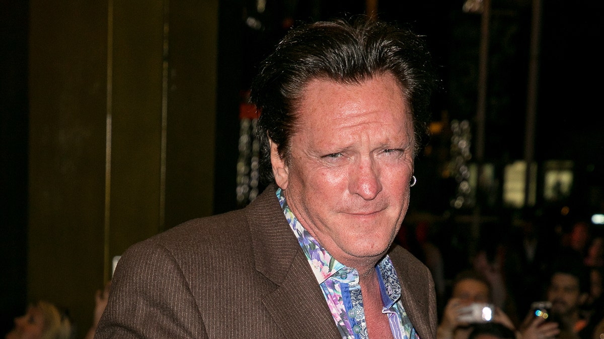 El actor Michael Madsen posa con un traje marrón.