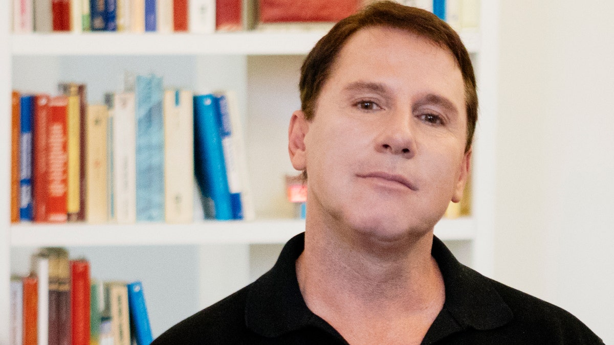 Nicholas Sparks posing in front of book shelf 