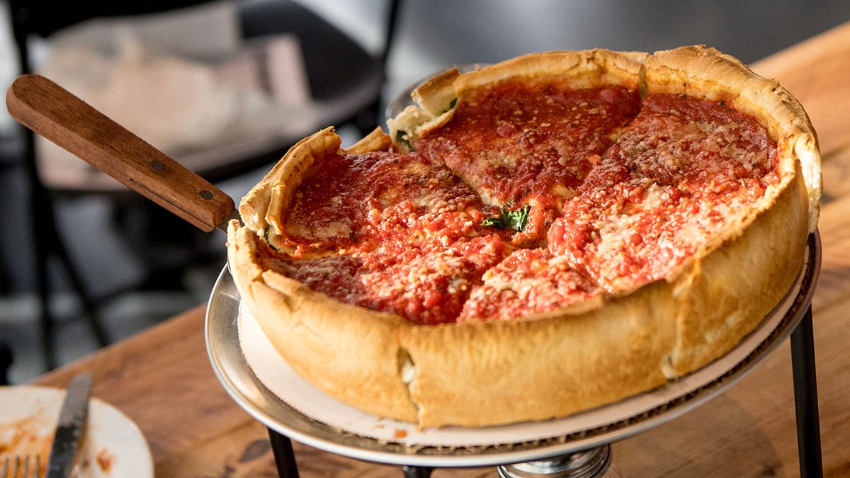 A deep dish pizza on a pizza rack.