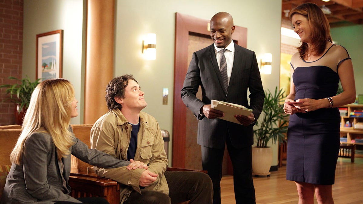 Gabriel Olds inn a tan jacket looks up at Taye Diggs in a black suit and Kate Walsh in a blue dress on an episode of "Private Practice"