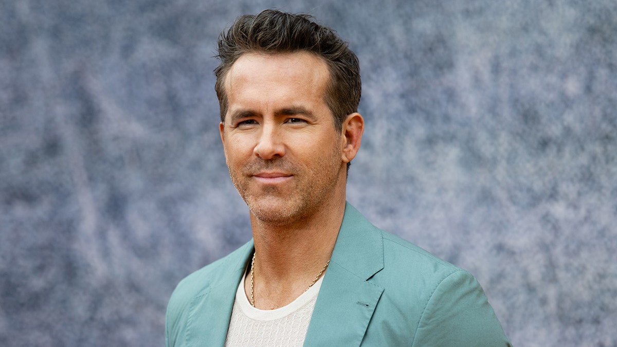 Ryan Reynolds in a turquoise blazer soft smiles on the carpet