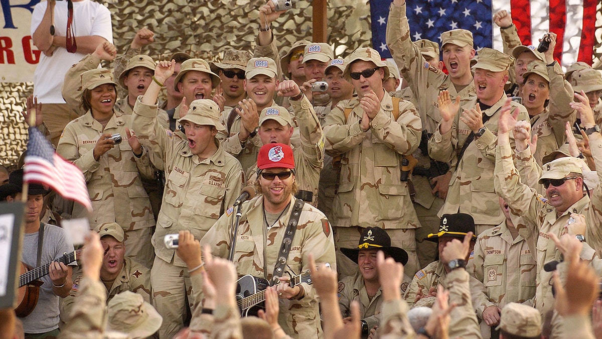 Toby Keith lleva un sombrero rojo mientras actúa para el Ejército.