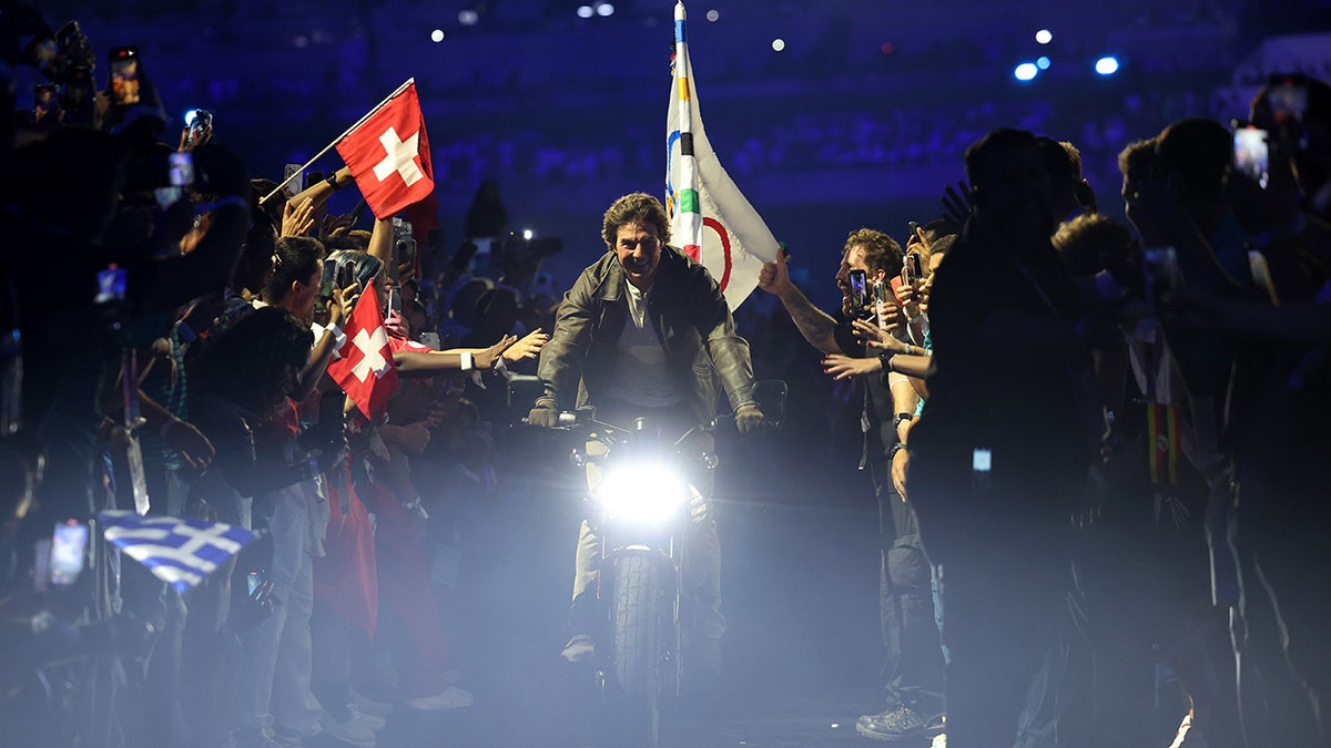 Tom Cruise rides a motorcycle at Paris Olympics.