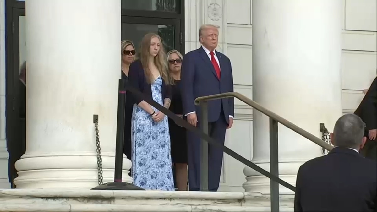 President Trump stands with a young woman on the steps of the Arlington wreath-laying ceremony