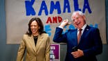 GLENDALE, ARIZONA - AUGUST 9: Democratic presidential candidate, U.S. Vice President Kamala Harris and Democratic vice presidential candidate Minnesota Gov. Tim Walz laugh after taking a selfie in front of a sign that reads "Kamala and The Coach" during stop at a campaign office on August 9, 2024 in Glendale, Arizona. Kamala Harris and her newly selected running mate Tim Walz are campaigning across the country this week. (Photo by Andrew Harnik/Getty Images)