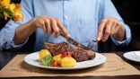 Man eating steak, with other foods on his plate, too