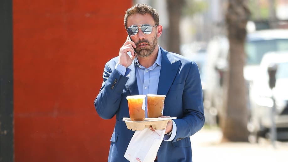 Ben Affleck al teléfono sosteniendo cafés Dunkin