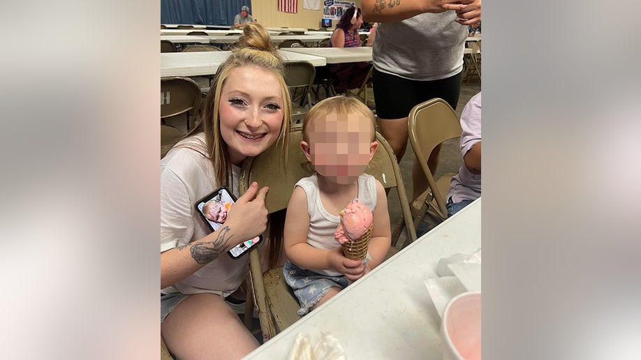 Kaitlynn Lee smiles in a t-shirt with a child