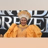 Connie Chiume in a golden yellow dress with puffy sleeves and a matching head piece at the "Wakanda Forever" premiere