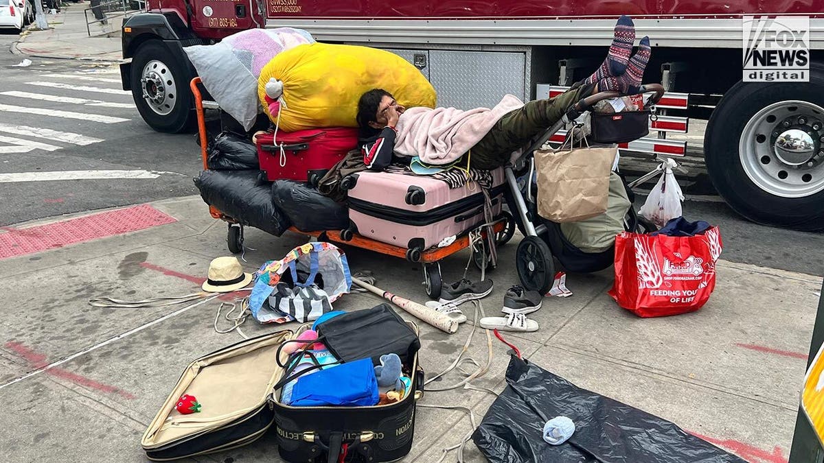 Un hombre dormido en una calle rodeado de basura y ropa