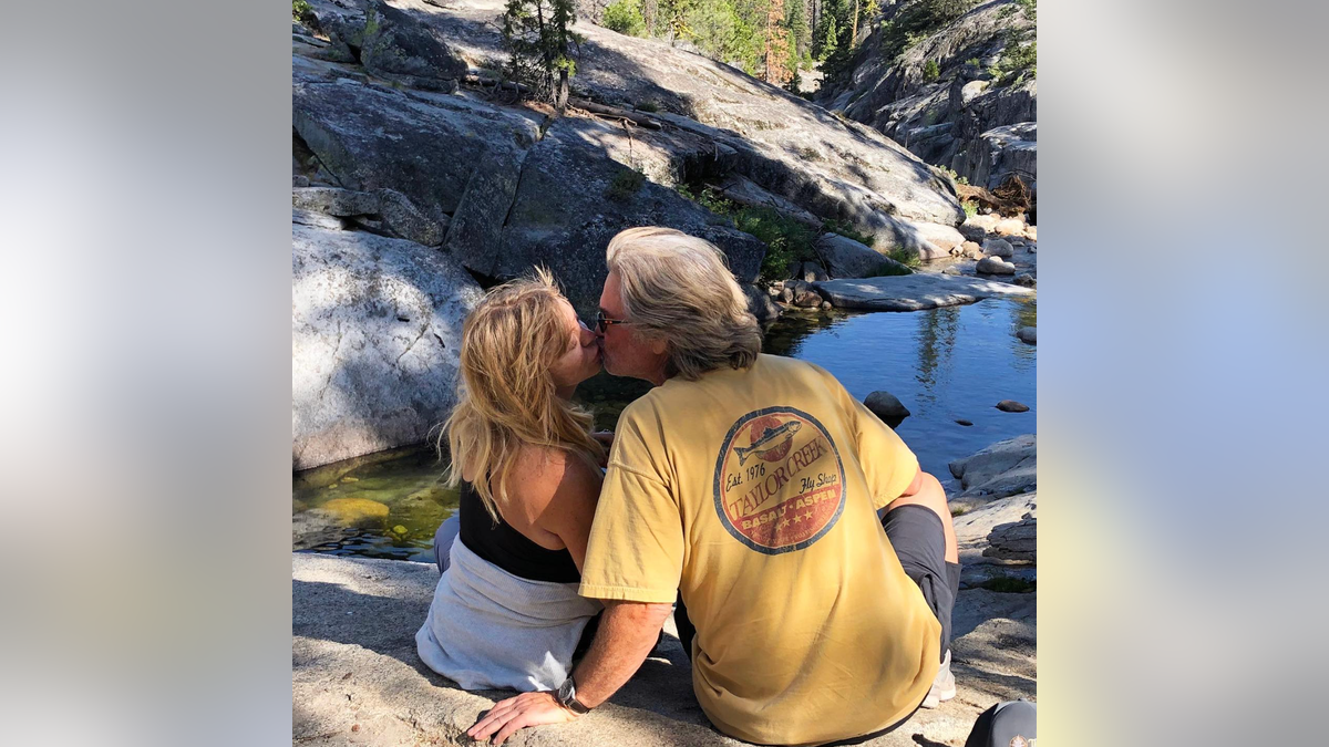 Goldie Hawn and Kurt Russell share a kiss on a rock 